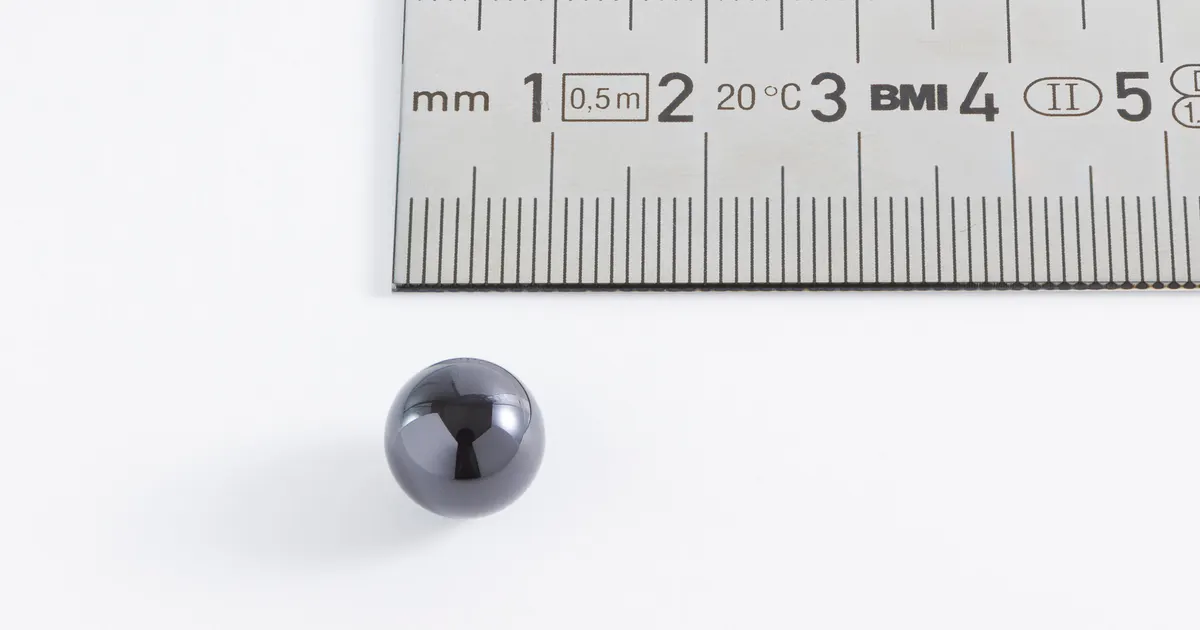 Silicon nitride bearing ball, 10 mm diameter, beside a steel rule
